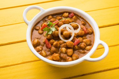 Baharatlı piliç bezelye köri veya Çola Masala veya Chana Masala veya chole bhature veya choley dilimlenmiş soğan ve yeşil kişniş yaprağı, seçici odak ile süslenmiş