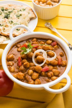 Baharatlı piliç bezelye köri veya Çola Masala veya Chana Masala veya chole bhature veya choley dilimlenmiş soğan ve yeşil kişniş yaprağı, seçici odak ile süslenmiş