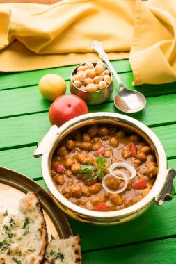 Baharatlı piliç bezelye köri veya Çola Masala veya Chana Masala veya chole bhature veya choley dilimlenmiş soğan ve yeşil kişniş yaprağı, seçici odak ile süslenmiş