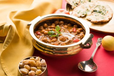 Baharatlı piliç bezelye köri veya Çola Masala veya Chana Masala veya chole bhature veya choley dilimlenmiş soğan ve yeşil kişniş yaprağı, seçici odak ile süslenmiş