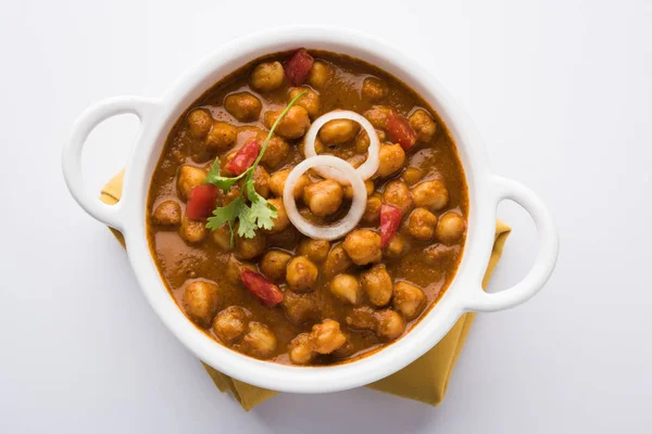 Baharatlı piliç bezelye köri veya Çola Masala veya Chana Masala veya chole bhature veya choley dilimlenmiş soğan ve yeşil kişniş yaprağı, seçici odak ile süslenmiş