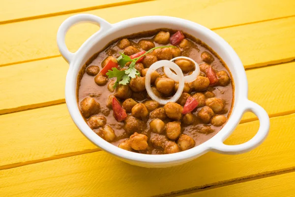 Baharatlı piliç bezelye köri veya Çola Masala veya Chana Masala veya chole bhature veya choley dilimlenmiş soğan ve yeşil kişniş yaprağı, seçici odak ile süslenmiş — Stok fotoğraf