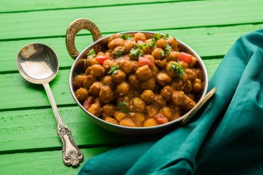 Baharatlı piliç bezelye köri veya Çola Masala veya Chana Masala veya chole bhature veya choley dilimlenmiş soğan ve yeşil kişniş yaprağı, seçici odak ile süslenmiş