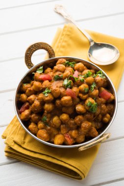 Baharatlı piliç bezelye köri veya Çola Masala veya Chana Masala veya chole bhature veya choley dilimlenmiş soğan ve yeşil kişniş yaprağı, seçici odak ile süslenmiş