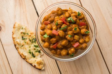 Baharatlı piliç bezelye köri veya Çola Masala veya Chana Masala veya chole bhature veya choley dilimlenmiş soğan ve yeşil kişniş yaprağı, seçici odak ile süslenmiş