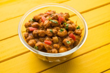 Baharatlı piliç bezelye köri veya Çola Masala veya Chana Masala veya chole bhature veya choley dilimlenmiş soğan ve yeşil kişniş yaprağı, seçici odak ile süslenmiş