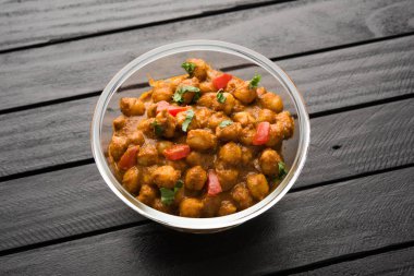 Baharatlı piliç bezelye köri veya Çola Masala veya Chana Masala veya chole bhature veya choley dilimlenmiş soğan ve yeşil kişniş yaprağı, seçici odak ile süslenmiş