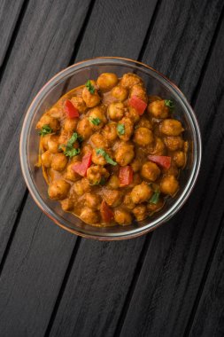 Baharatlı piliç bezelye köri veya Çola Masala veya Chana Masala veya chole bhature veya choley dilimlenmiş soğan ve yeşil kişniş yaprağı, seçici odak ile süslenmiş