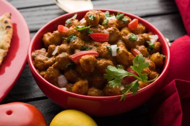 Baharatlı piliç bezelye köri veya Çola Masala veya Chana Masala veya chole bhature veya choley dilimlenmiş soğan ve yeşil kişniş yaprağı, seçici odak ile süslenmiş