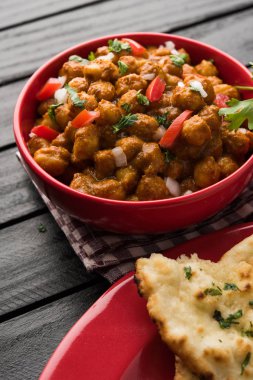 Baharatlı piliç bezelye köri veya Çola Masala veya Chana Masala veya chole bhature veya choley dilimlenmiş soğan ve yeşil kişniş yaprağı, seçici odak ile süslenmiş