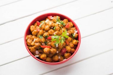 Baharatlı piliç bezelye köri veya Çola Masala veya Chana Masala veya chole bhature veya choley dilimlenmiş soğan ve yeşil kişniş yaprağı, seçici odak ile süslenmiş