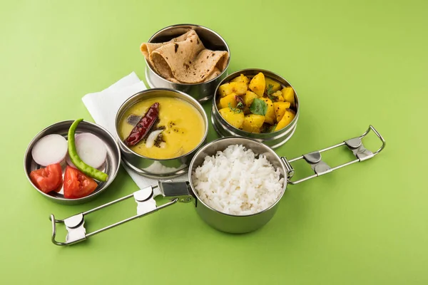 Indisch typische Edelstahl Lunchbox oder Tiffin mit nordindischen oder maharashtrischen Speisen wie Chapati / / roti, dal tadka, weißem Reis und aloo / potato sabji / gobi oder Blumenkohl sabji mit Salat — Stockfoto