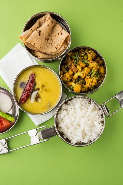 Save Download Preview indian typical stainless steel lunch box or tiffin with north indian or maharashtrian food menu like chapati//roti, dal tadka, white rice and aloo / potato sabji / gobi or cauliflower sabji with salad