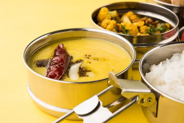 Guardar Descargar Previsualizar la caja de almuerzo india típica de acero inoxidable o tiffin con menú de alimentos del norte indio o maharashtriano como chapati / / roti, dal tadka, arroz blanco y aloo / potato sabji / gobi o coliflor sabji con ensalada — Foto de Stock