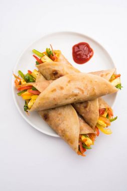 Indian popular snack food called Vegetable spring rolls or veg roll or veg franky made using paneer or cottage cheese and vegetables wrapped inside paratha/chapati/roti with tomato ketchup clipart