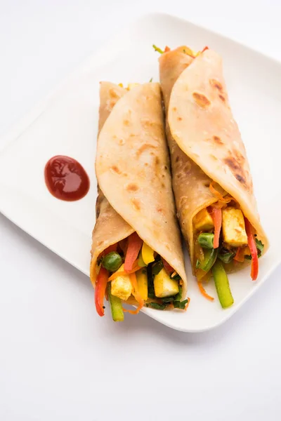 Indian popular snack food called Vegetable spring rolls or veg roll or veg franky made using paneer or cottage cheese and vegetables wrapped inside paratha/chapati/roti with tomato ketchup