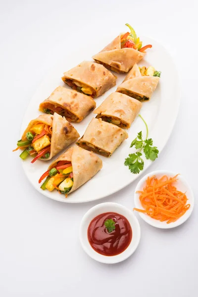 Indian popular snack food called Vegetable spring rolls or veg roll or veg franky made using paneer or cottage cheese and vegetables wrapped inside paratha/chapati/roti with tomato ketchup