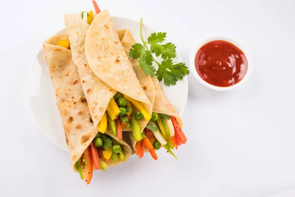 Indian popular snack food called Vegetable spring rolls or veg franky made using vegetables wrapped inside paratha/chapati/roti with tomato ketchup