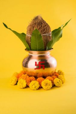 Bakır kalash Hindistan cevizi ve mango yaprak çiçek dekorasyonu ile. hindu puja, düz arka plan üzerinde seçici odak uçucu