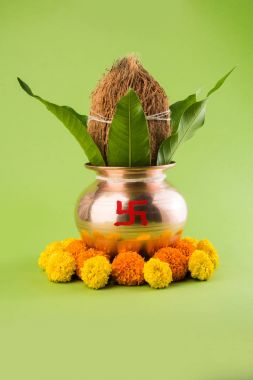 Bakır kalash Hindistan cevizi ve mango yaprak çiçek dekorasyonu ile. hindu puja, düz arka plan üzerinde seçici odak uçucu
