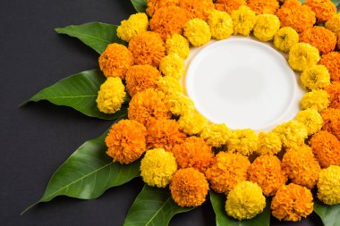 kadife çiçeği veya zendu çiçek ve mango kullanılarak yapılan çiçek rangoli kopya alanı orta, seçici odak ile siyah arka plan üzerinde bırakır