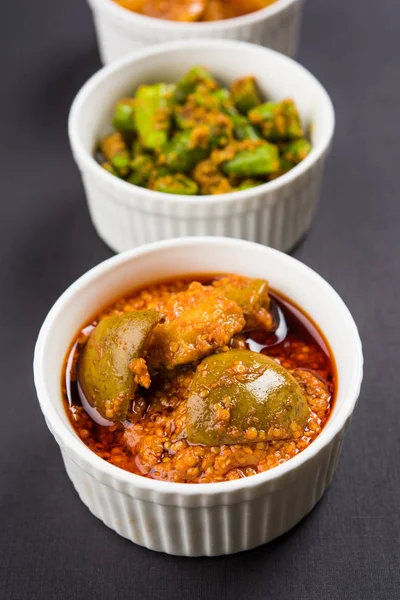 Group photograph of indian pickles like mango pickle , lemon pickle and green chilli pickle, sarved in ceramic bowls, selective focus