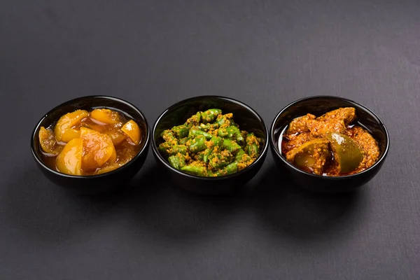 Group photograph of indian pickles like mango pickle , lemon pickle and green chilli pickle, sarved in ceramic bowls, selective focus