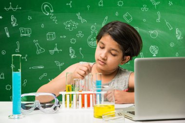 Çocuklar ve bilim kavramı - sevimli Hint küçük kız meşgulken bilim veya kimya tüp ve Emanet göz cam şişeye yeşil kara tahta arka plan üzerinde çizilmiş bilim karalamalar ile denemek
