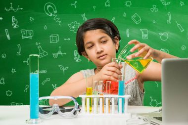Çocuklar ve bilim kavramı - sevimli Hint küçük kız meşgulken bilim veya kimya tüp ve Emanet göz cam şişeye yeşil kara tahta arka plan üzerinde çizilmiş bilim karalamalar ile denemek