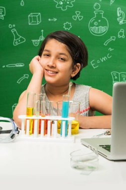 Çocuklar ve bilim kavramı - sevimli Hint küçük kız meşgulken bilim veya kimya tüp ve Emanet göz cam şişeye yeşil kara tahta arka plan üzerinde çizilmiş bilim karalamalar ile denemek