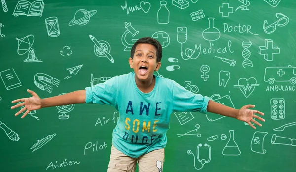 Criança da escola indiana em pé na frente de quadro verde com doodles ciência / educação e mostrando felicidade por causa da vitória com as mãos esticadas — Fotografia de Stock