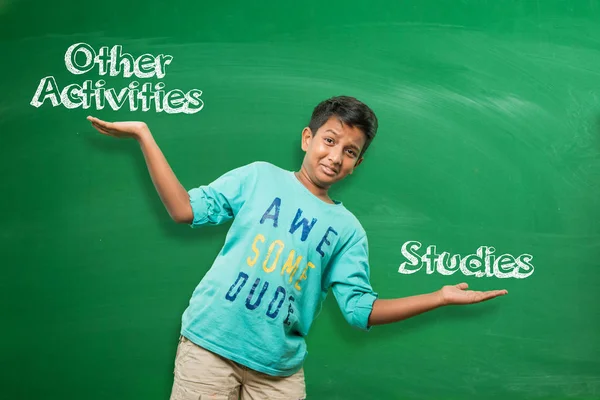 Niño de la escuela india o niño de pie frente a pizarra verde con ambas manos estiradas, presentando algún concepto con espacio de copia — Foto de Stock