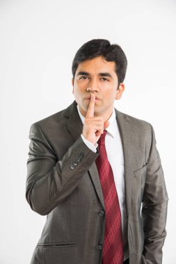 Hintli genç işadamı tutmak ağız, beyaz arka plan üzerinde izole ayakta kapsayan süre sessizlik poz