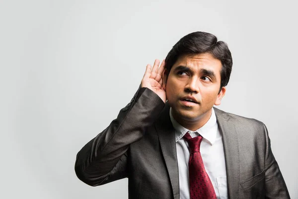 Jovem empresário indiano ouvindo algo sobre fundo branco — Fotografia de Stock