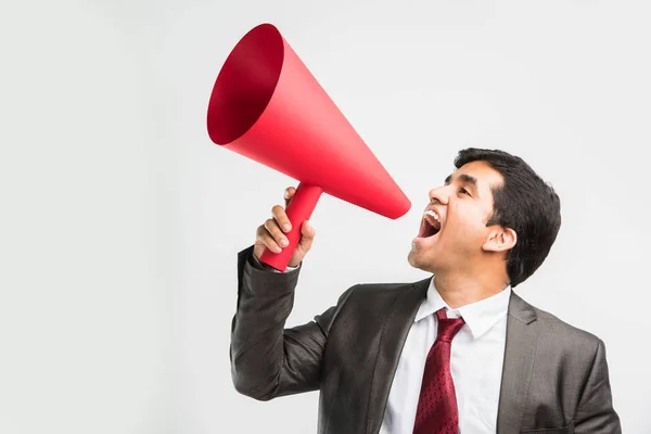 Uomo d'affari indiano che annuncia o diffonde notizie utilizzando altoparlanti rossi o mega microfono fatto di carta, isolato su sfondo bianco — Foto Stock