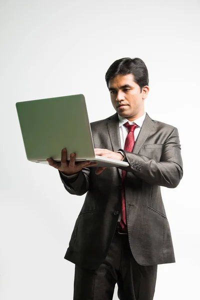 Retrato del joven empresario indio confiado que trabaja en su computadora o portátil en la oficina, Empresario que usa una computadora portátil y sonríe de pie aislado sobre un fondo blanco — Foto de Stock