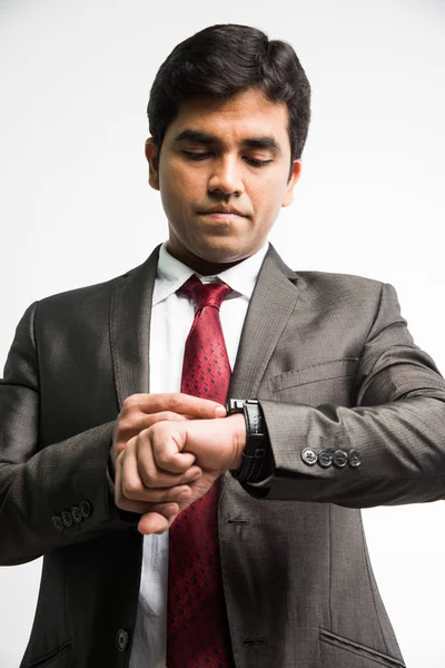 Tiempo es el concepto de dinero - joven empresario indio mirando / tiempo de ajuste en reloj de pulsera, de pie aislado sobre fondo blanco — Foto de Stock