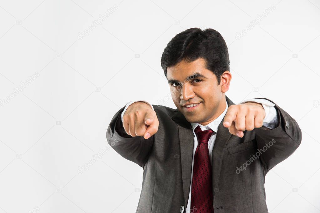 I want you concept - young indian businessman choosing you by pointing index fingers of both hands at camera or you, standing isolated over white background