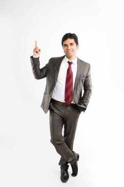 Hintli genç işadamı ise bir şeye işaret parmağı dengeleme ve takım elbise ve kravat, beyaz arka plan üzerinde izole gibi tam kurumsal kıyafetleri giyen kameraya bakarak tam pic