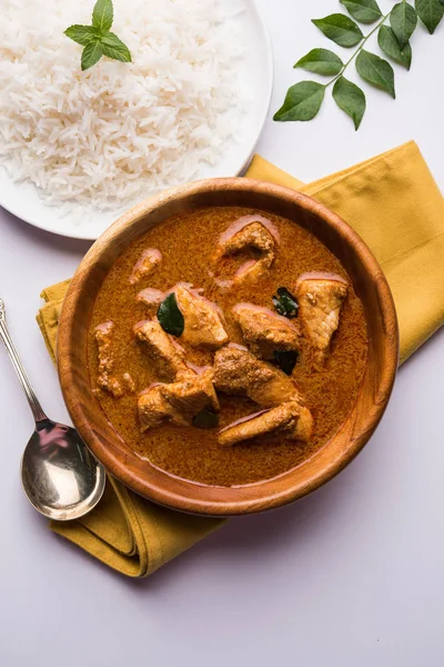 tasty fish curry served with white cooked basmati rice with curry leaves in the background, favourite coastal indian food