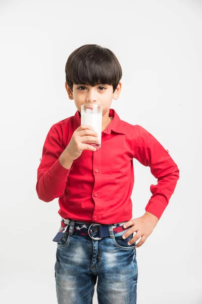 Schattige kleine Indiase jongen drinken van gewone melk of een glas melk, vol te houden op witte achtergrond — Stockfoto