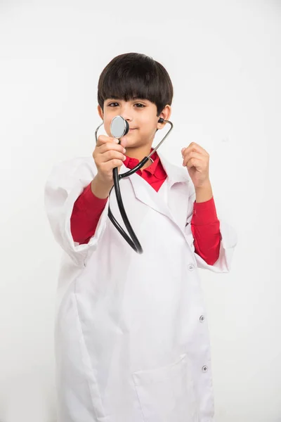 Indio lindo niño o niño en uniforme de médico con estetoscopio y alcancía en la mano —  Fotos de Stock