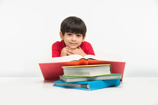 Indien mignon petit garçon ou enfant lecture livre sur table d'étude, isolé sur fond blanc — Photo