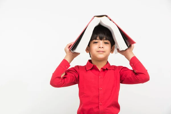 Індійський милий хлопчик або хлопчик тримає книгу над головою, ізольований на білому тлі — стокове фото
