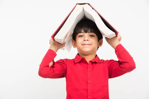 Indiana bonito criança ou menino segurando livro sobre cabeça, isolado sobre fundo branco — Fotografia de Stock