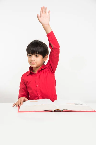 Indian cute little boy or kid reading book over study table, isolated over white background — Stock Photo, Image