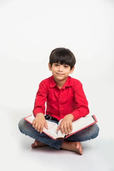Симпатичный Маленький Индийский Мальчик Читает Книгу Сидя Лежа Белом Фоне — стоковое фото