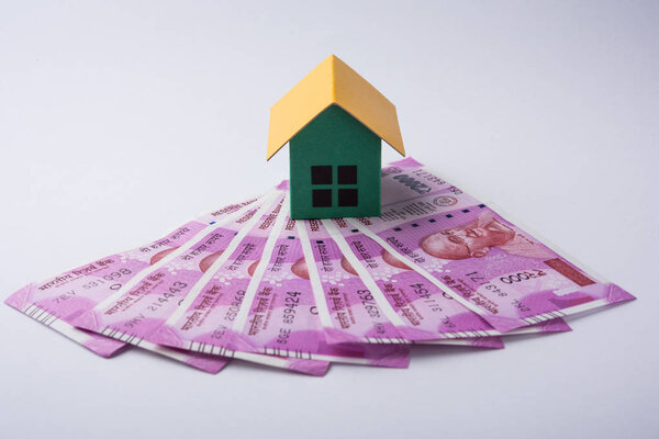 indian rupees and house model  isolated on  background