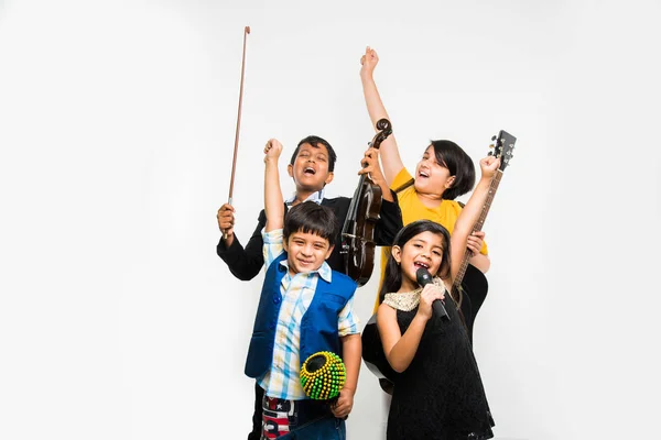 Niños indios tocando y cantando mientras tocan guitarra, violín, flauta, instrumento musical menor, etc en una banda, aislados sobre fondo blanco — Foto de Stock