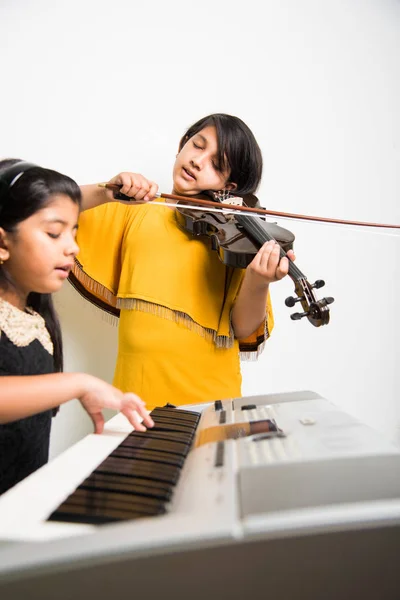 Çocuklar ve müzik konsepti - müzik aletleri oynayan Hintli küçük kızlar piyano veya klavye ya da keman gibi — Stok fotoğraf